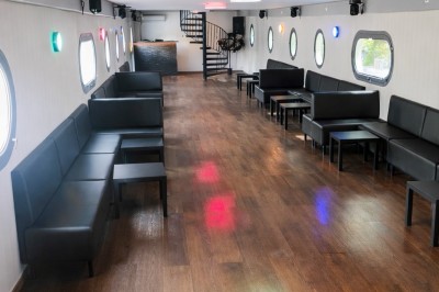 Table élégamment dressée avec nappes blanches, serviettes pliées, verres et décorations florales dans une salle lumineuse.