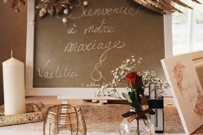Table élégamment dressée avec nappes blanches, serviettes pliées, verres et décorations florales dans une salle lumineuse.