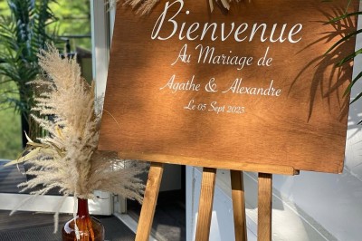 Table élégamment dressée avec nappes blanches, serviettes pliées, verres et décorations florales dans une salle lumineuse.