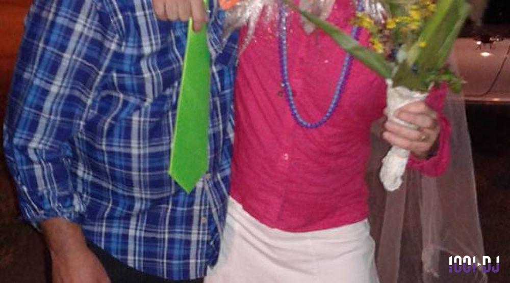 Deux personnes déguisées, l'une en chemise à carreaux et cravate verte, l'autre en tenue rose avec un bouquet de fleurs.