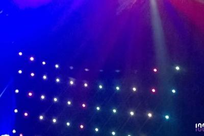 Un couple danse dans une salle faiblement éclairée avec des lumières colorées et une ambiance festive.