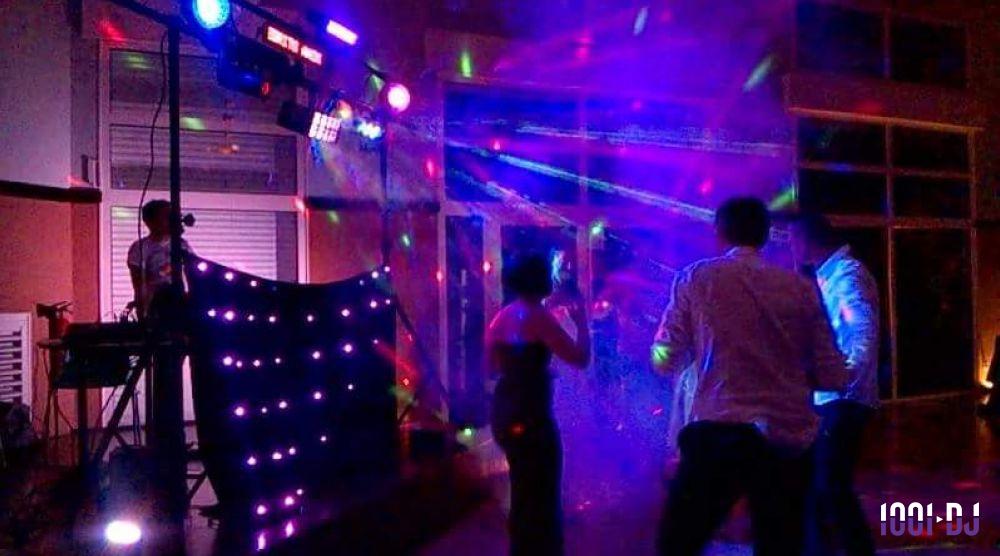 Des personnes dansent sous des jeux de lumière colorés lors d'une soirée animée par un DJ.