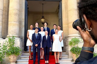 Miniature MHBA - Mon Hôte-sse Bien Aimé-e #13 Quatre femmes en robe noire sourient debout sur une terrasse en bois avec un fond de verdure.