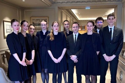 Miniature MHBA - Mon Hôte-sse Bien Aimé-e #9 Quatre femmes en robe noire sourient debout sur une terrasse en bois avec un fond de verdure.