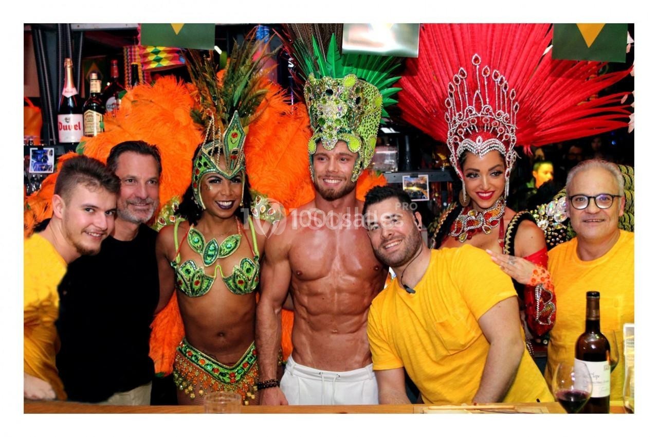 Des personnes souriantes posent ensemble, dont des danseurs en costumes colorés et des participants en tenue décontractée.