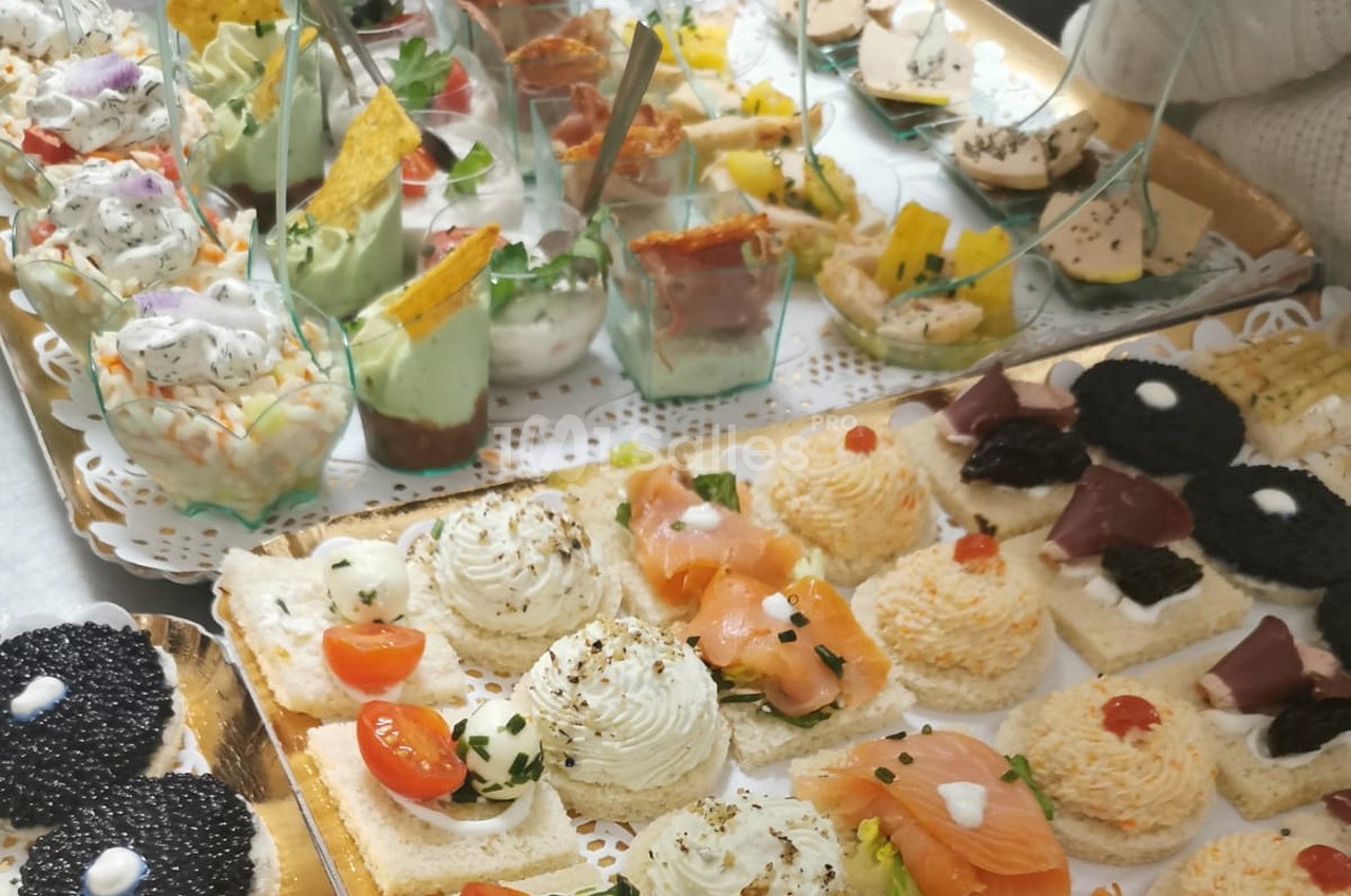 Plateau de canapés variés avec saumon, caviar, mousse et verrines colorées, présenté sur des nappes en dentelle.