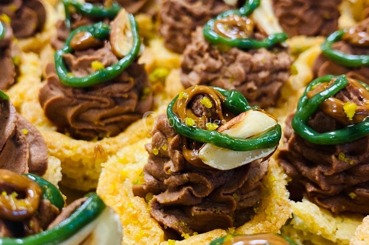 Petits desserts décorés de crème au chocolat, amandes et glaçage vert sur une base croustillante.