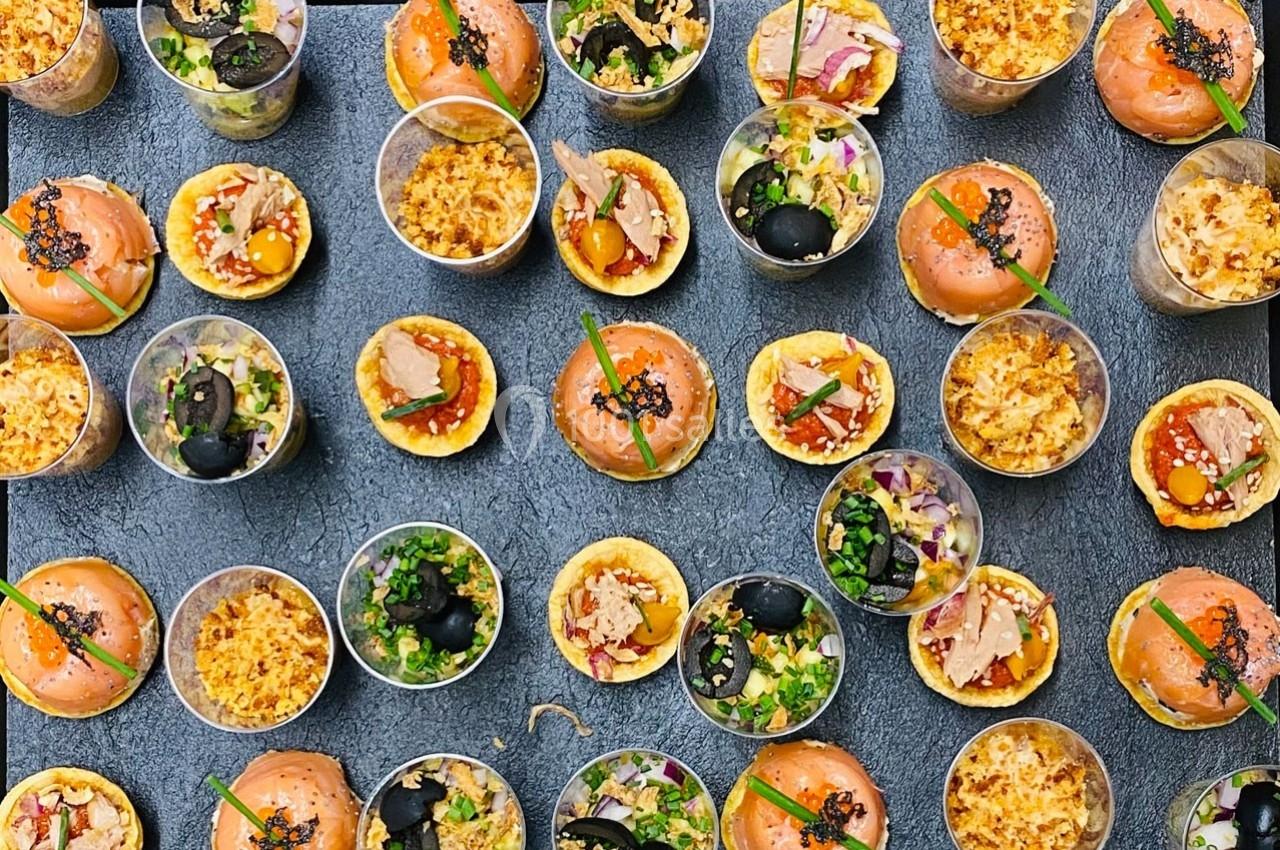 Plateau de verrines et bouchées variées, comprenant tartares, tartelettes et garnitures colorées.