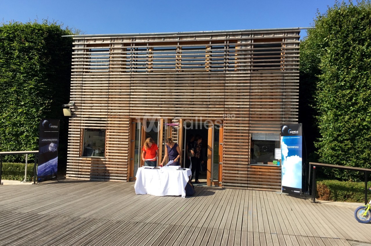Façade en bois d'un bâtiment moderne avec des personnes rassemblées devant une table blanche à l'entrée.