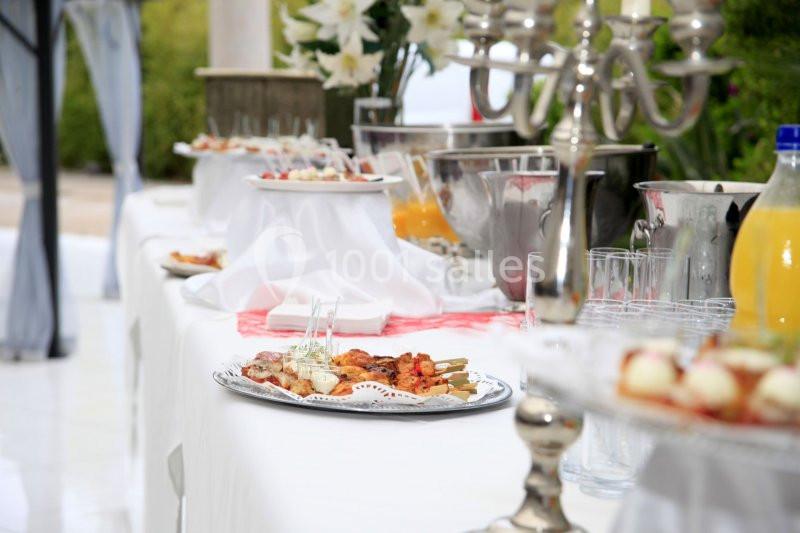 Buffet dressé avec divers plats, boissons et décorations élégantes dans un cadre extérieur.