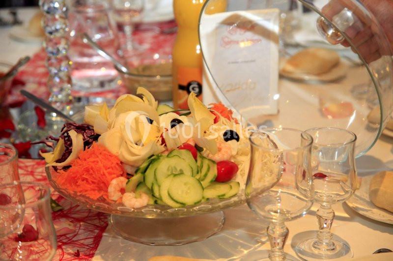 Plat de crudités variées avec concombres, carottes, endives, olives et crevettes, présenté sur une table dressée.