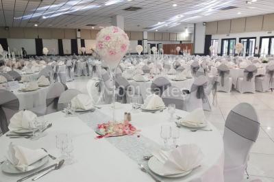 Lettres rouges formant le mot ’LOVE’ sur un tapis rouge, entourées de petites décorations blanches, en extérieur.