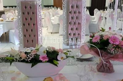 Lettres rouges formant le mot ’LOVE’ sur un tapis rouge, entourées de petites décorations blanches, en extérieur.