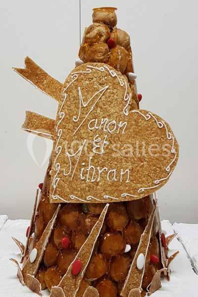 Pièce montée en choux décorée de nougatine en forme de cœur avec les prénoms ’Manon et Yihran’ inscrits dessus.