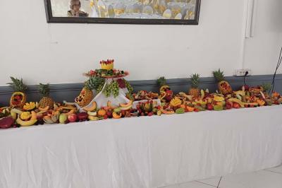 Lettres rouges formant le mot ’LOVE’ sur un tapis rouge, entourées de petites décorations blanches, en extérieur.