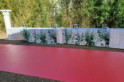 Lettres rouges formant le mot ’LOVE’ sur un tapis rouge, entourées de petites décorations blanches, en extérieur.