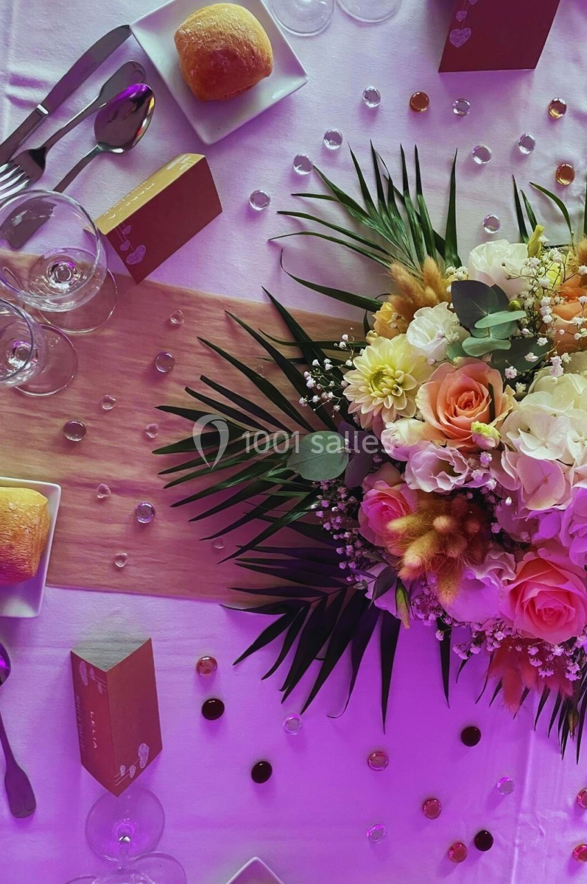 Table décorée avec un bouquet de fleurs colorées, des couverts, des verres, des petits pains et des boîtes cadeaux.