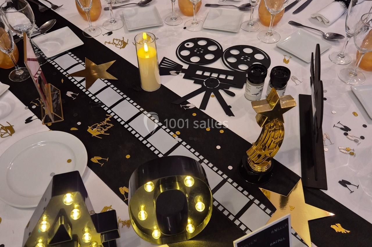 Décoration de table sur le thème du cinéma avec éléments dorés, noirs et lumineux, incluant un chiffre ’40’ éclairé.
