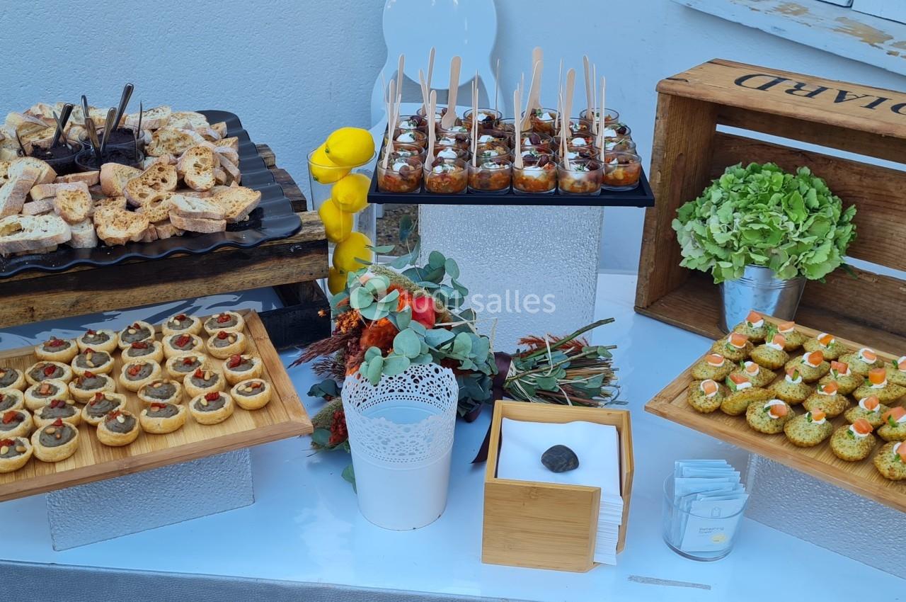 Buffet de bouchées apéritives variées disposées sur des plateaux en bois et en métal, décoré de plantes et d'éléments…