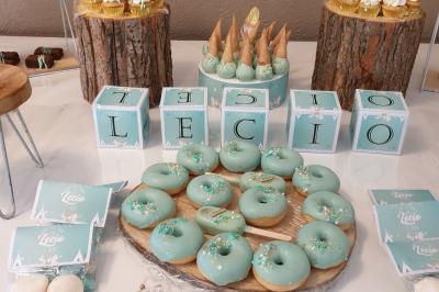 Table décorée pour une fête avec des donuts glacés bleus, des cubes décoratifs et des desserts variés sur des supports en…
