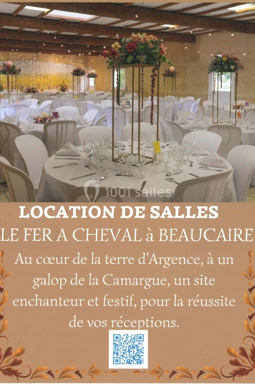 Salle de réception décorée avec des tables rondes, nappes blanches, chandeliers et fleurs, sous une charpente en bois.