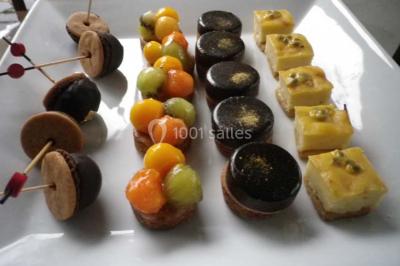 Miniature Traiteur Magny-en-Vexin (Val-d'Oise) - Karen Réceptions Organisation #24 Corbeille garnie de fruits variés et fleurs décoratives, posée sur une table dans un environnement faiblement éclairé.