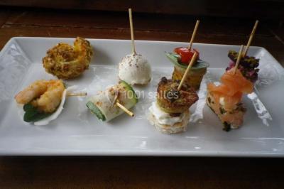 Miniature Traiteur Magny-en-Vexin (Val-d'Oise) - Karen Réceptions Organisation #5 Corbeille garnie de fruits variés et fleurs décoratives, posée sur une table dans un environnement faiblement éclairé.