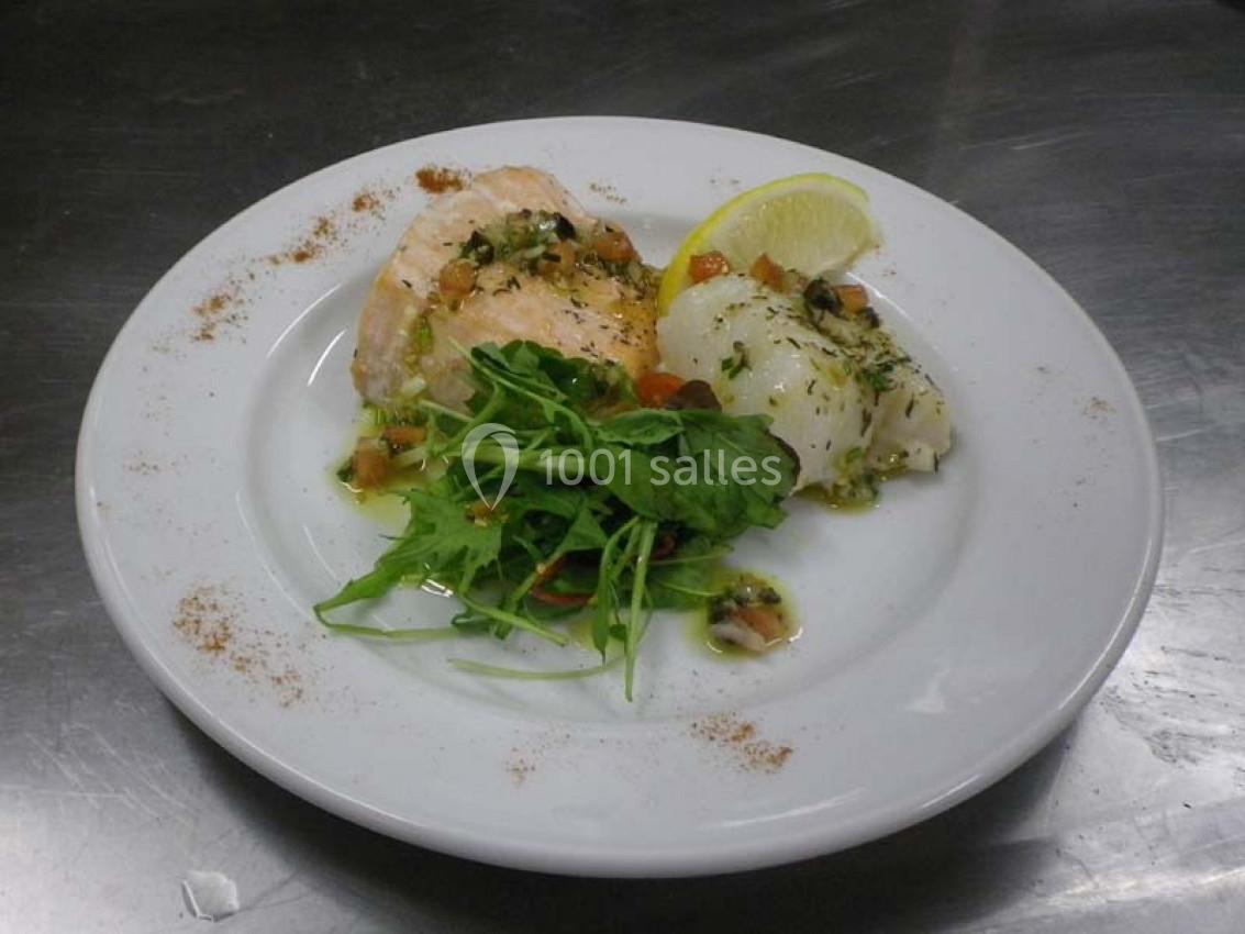Assiette contenant du poisson accompagné de roquette, d'une tranche de citron et d'une sauce aux herbes.