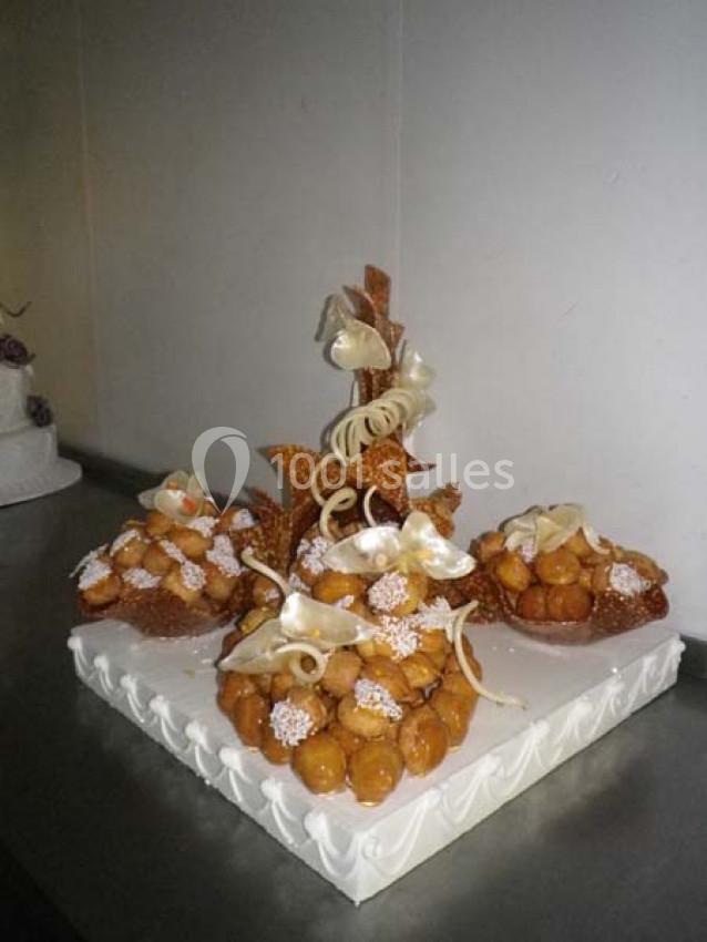 Pièce montée en choux caramélisés décorée de rubans en sucre et présentée sur un socle blanc.