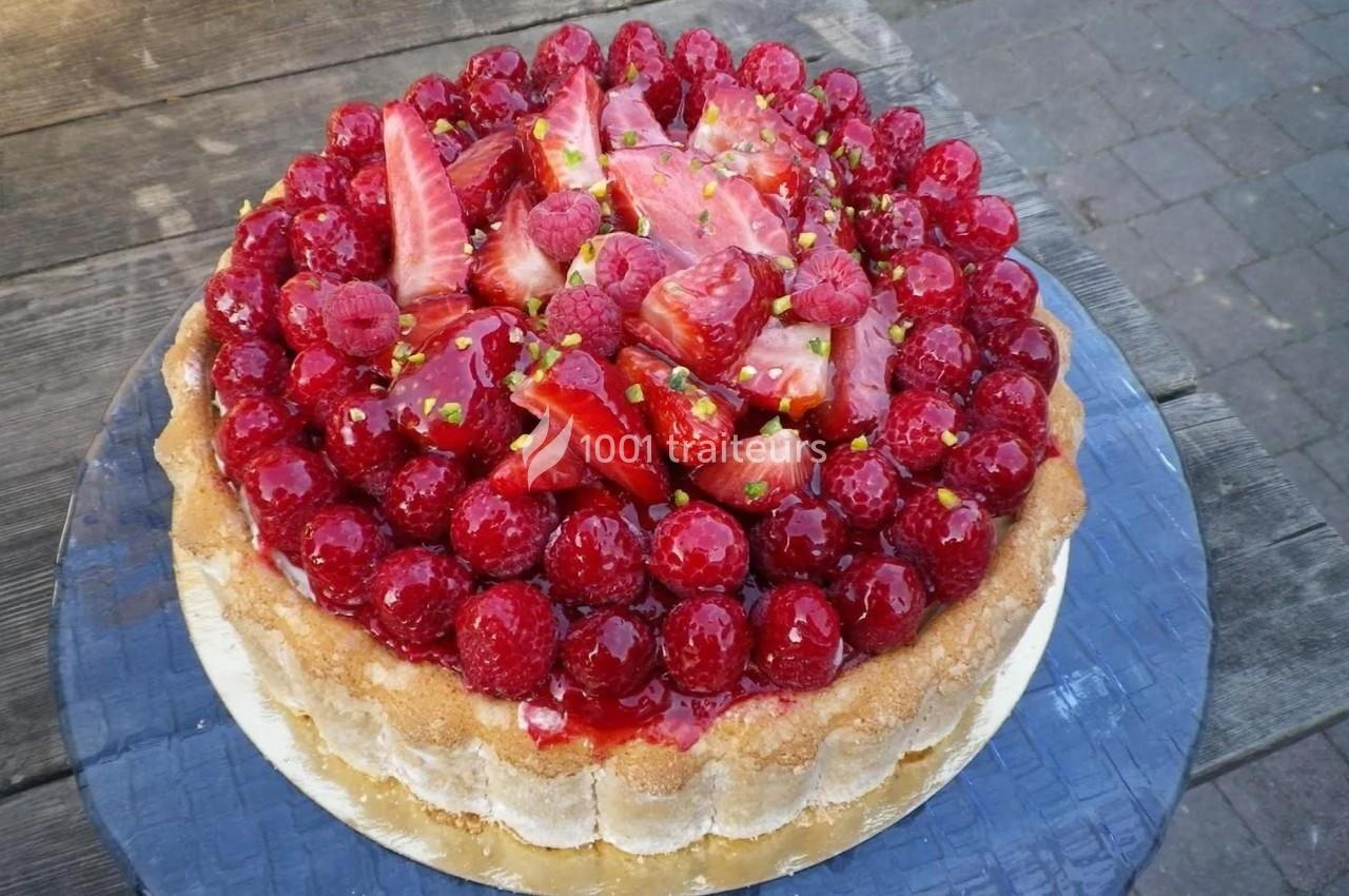 Tarte garnie de fraises et framboises fraîches sur une base de biscuit, posée sur une table en bois.