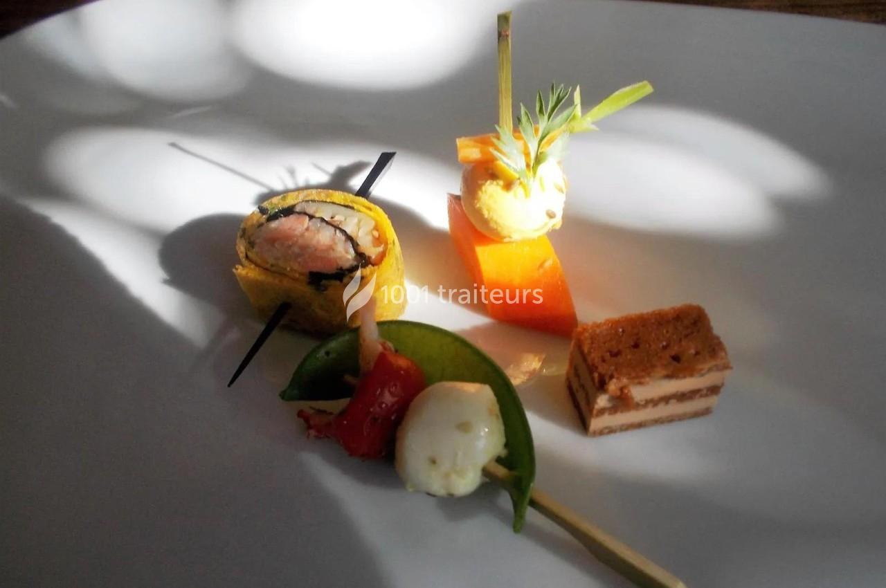 Assortiment de bouchées gastronomiques sur une assiette blanche, comprenant sushi, légumes et pâtisserie.