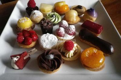 Corbeille garnie de fruits variés et fleurs décoratives, posée sur une table dans un environnement faiblement éclairé.