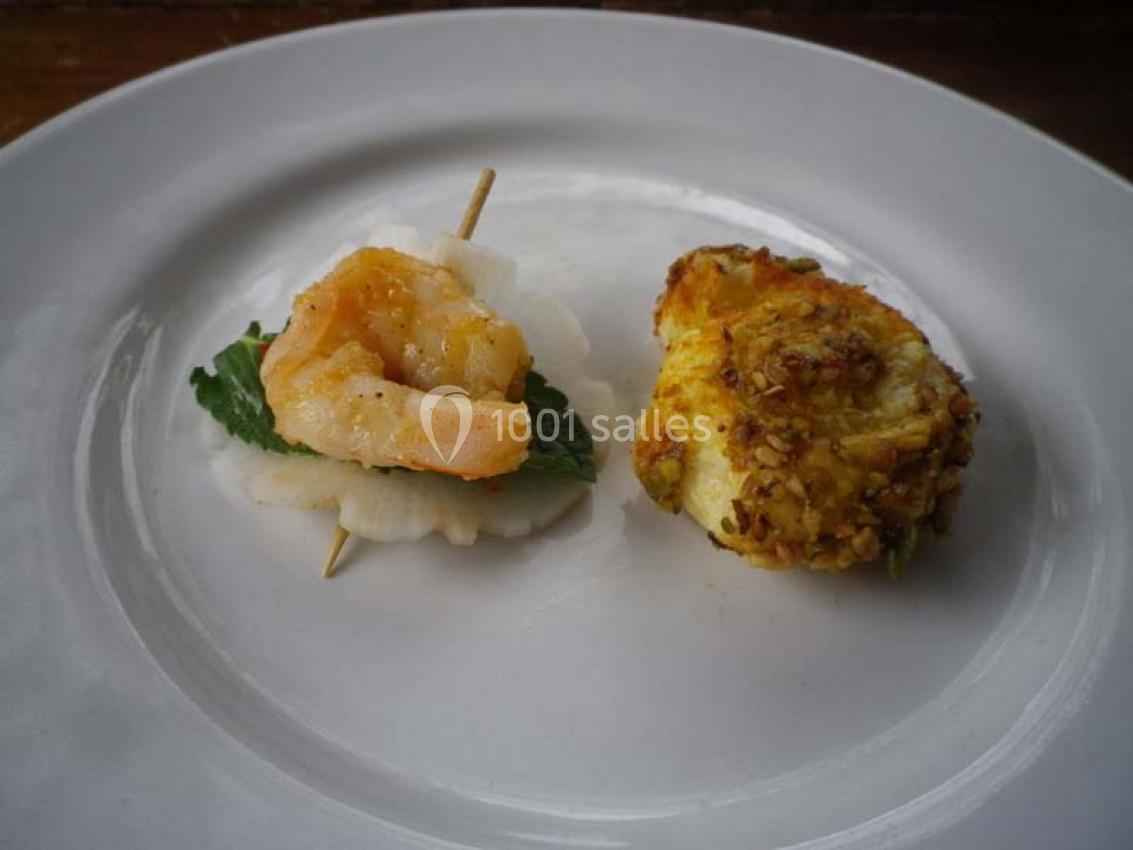 Crevette sur radis et feuille verte à gauche, croquette dorée à droite, présentées sur une assiette blanche.