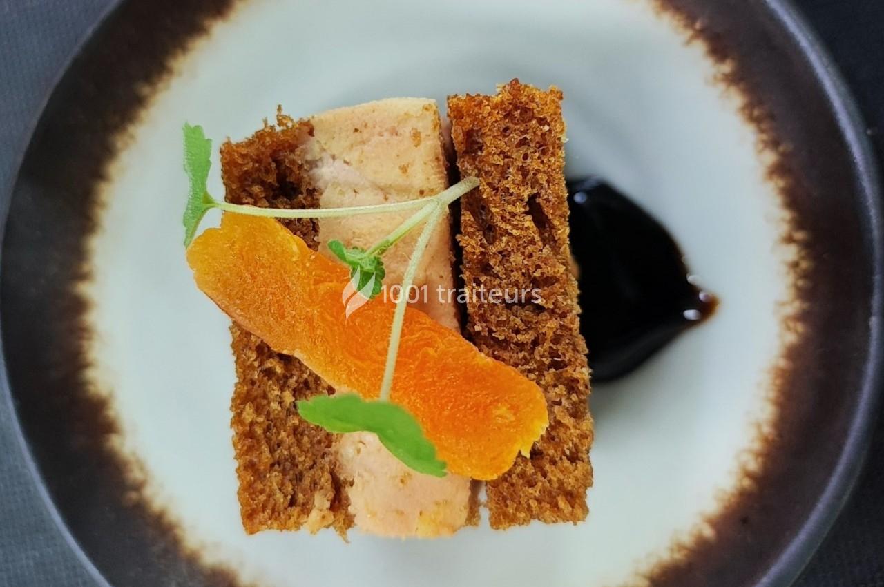 Tranche de foie gras entre deux morceaux de pain d'épices, garnie de fines herbes et d'une touche de gelée noire.