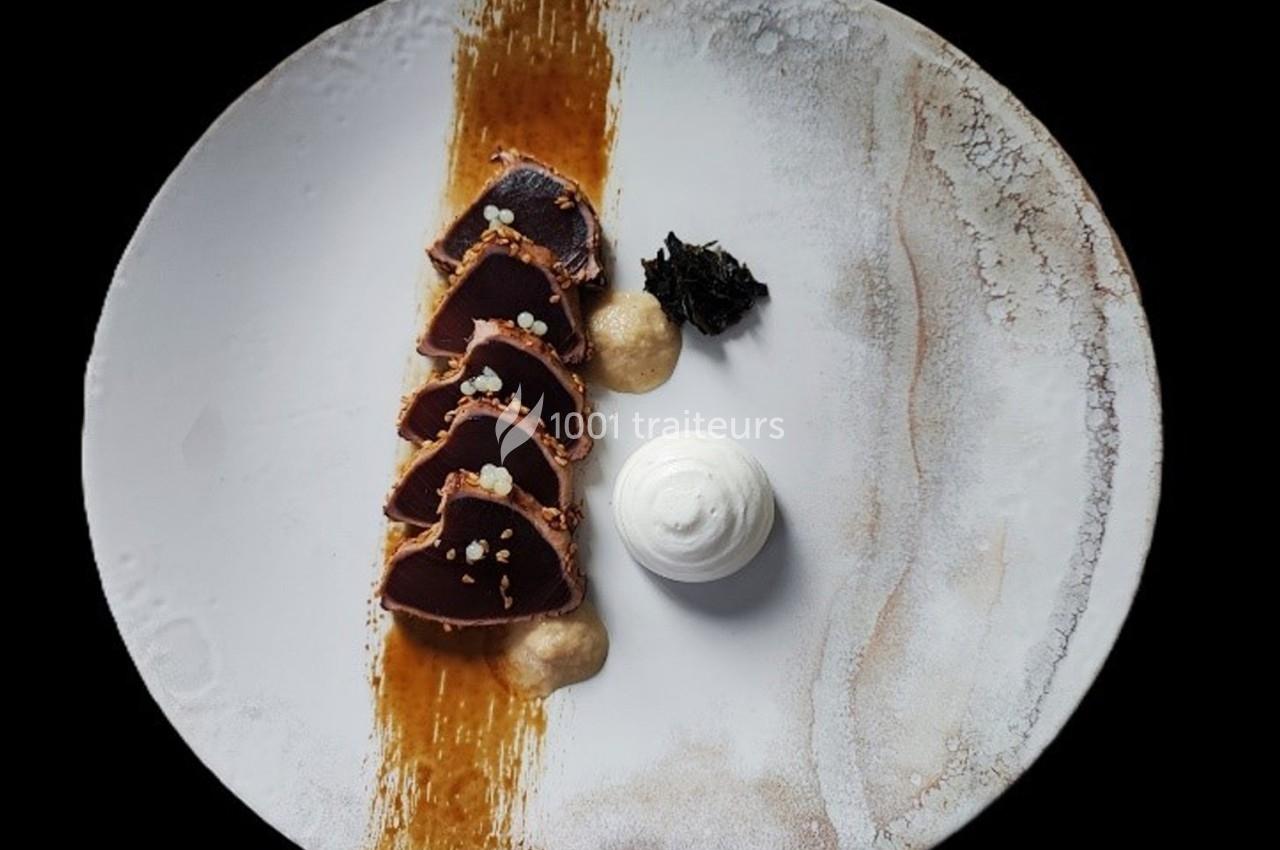 Tranches de thon mi-cuit disposées sur une sauce, accompagnées de mousse blanche et d'algues sur une assiette blanche.