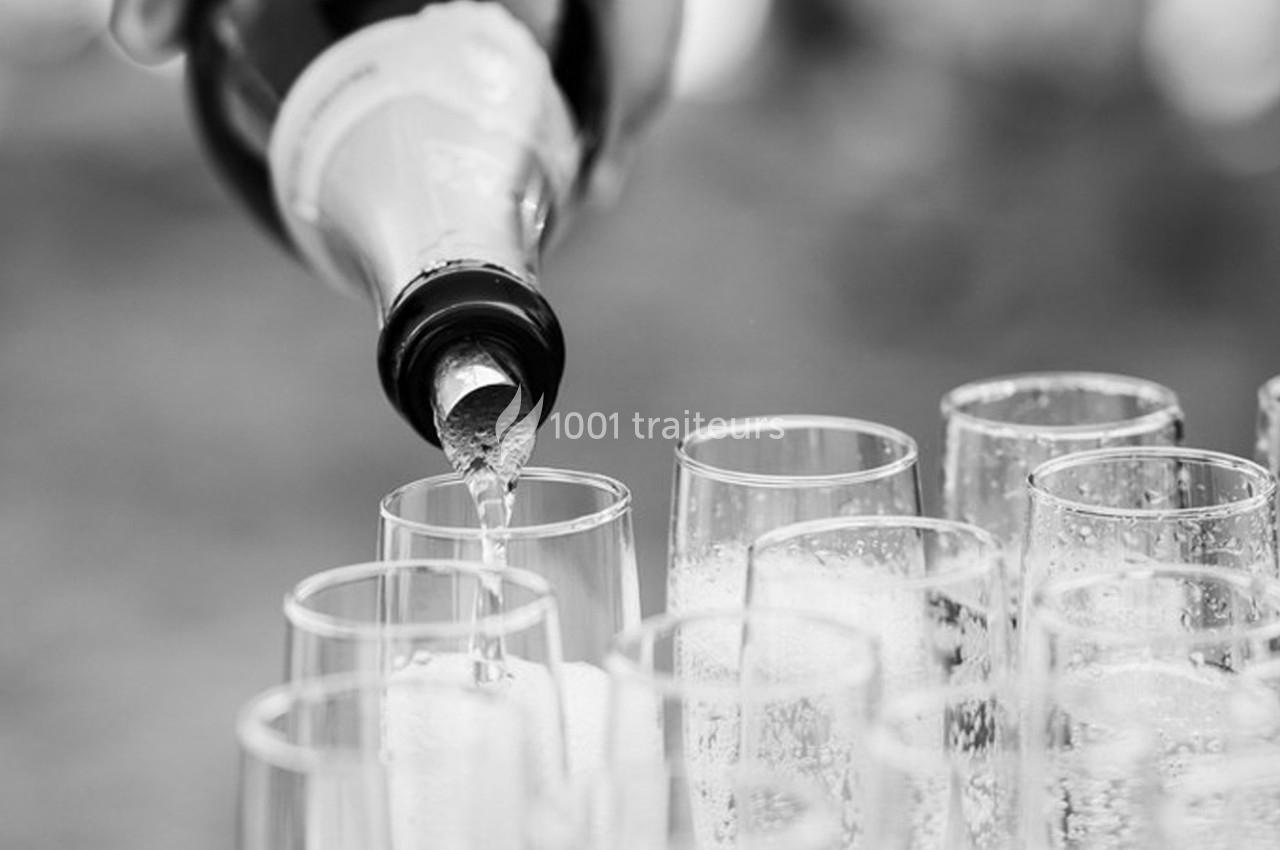 Bouteille versant du champagne dans plusieurs flûtes alignées sur une table.
