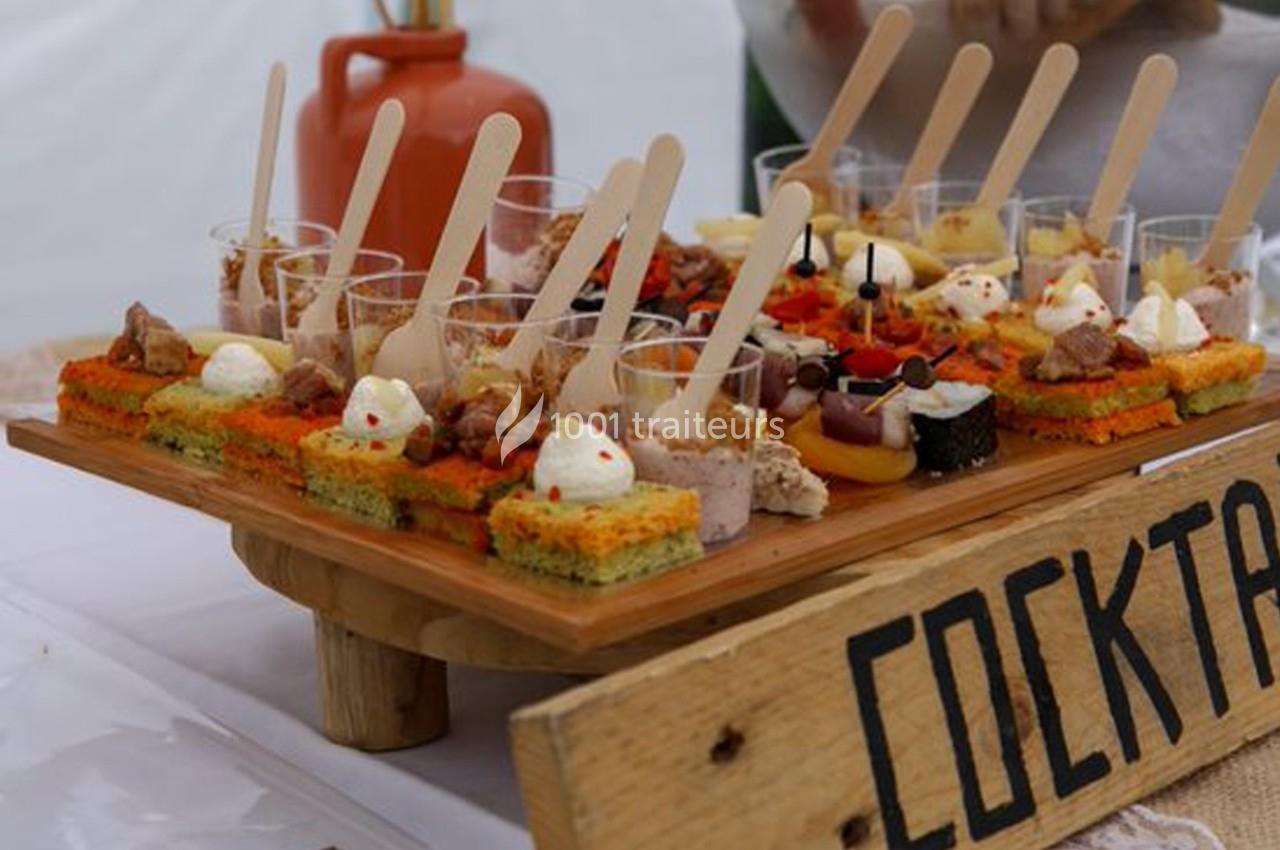Plateau de bouchées apéritives variées présentées sur des supports en bois, avec une pancarte ’Cocktail’.