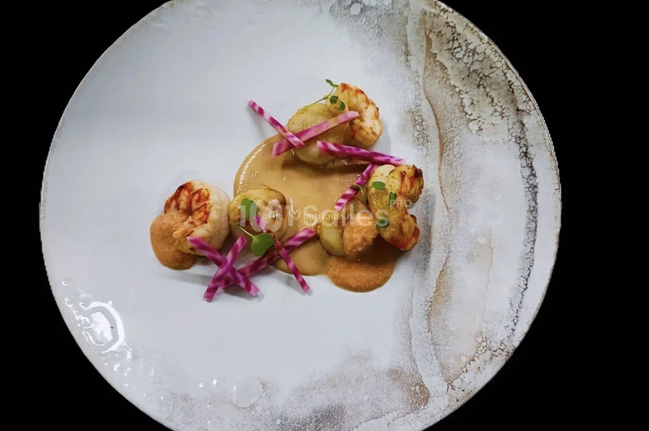 Assiette gastronomique avec crevettes grillées, sauce crémeuse, légumes croquants et présentation artistique.