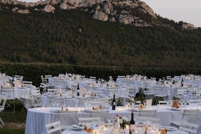 Miniature Traiteur Aix-en-Provence (Bouches-du-Rhône) - Carré Gourmand #24 Table dressée avec nappes blanches, verres à vin, couverts, petits pains et centre de table floral dans une salle lumineuse.