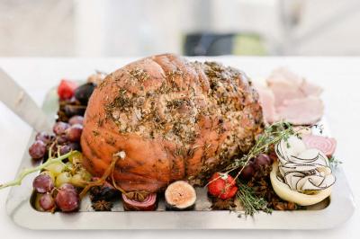 Une mariée en robe blanche tient un bouquet dans une salle décorée pour un mariage, avec un homme en costume bleu derrière…
