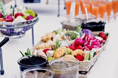 Une mariée en robe blanche tient un bouquet dans une salle décorée pour un mariage, avec un homme en costume bleu derrière…