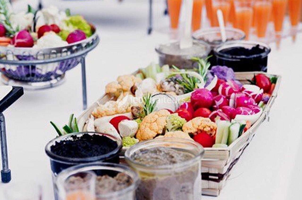 Plateau de légumes colorés avec sauces en pots, présenté sur une table blanche pour un buffet ou apéritif.
