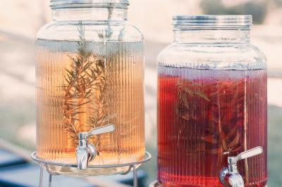 Une mariée en robe blanche tient un bouquet dans une salle décorée pour un mariage, avec un homme en costume bleu derrière…