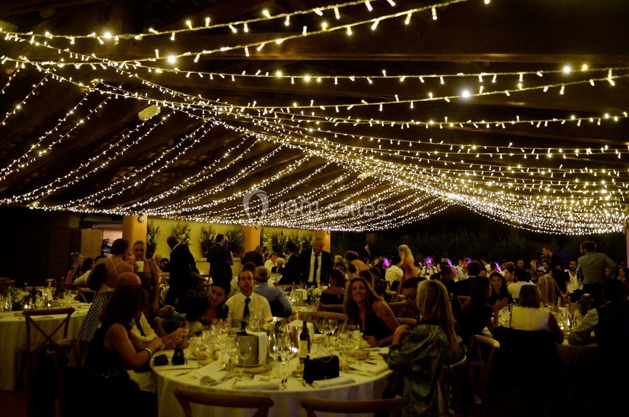Location salle Marsillargues (Hérault) - Le Mas Saint Gabriel #11 Salle de réception décorée de guirlandes lumineuses, avec des invités assis à des tables rondes.