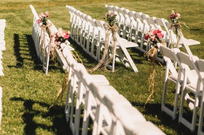Miniature Location salle Marsillargues (Hérault) - Le Mas Saint Gabriel #12 Une mariée souriante brandit un éventail devant un gâteau de mariage décoré, entourée d'invités en extérieur.