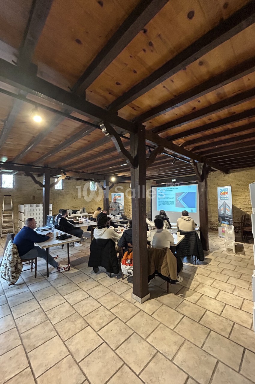 Des personnes assises dans une salle en bois assistent à une présentation projetée sur un écran.