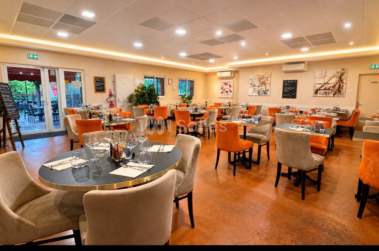 Salle de restaurant lumineuse avec tables dressées, chaises colorées et décorations murales modernes.