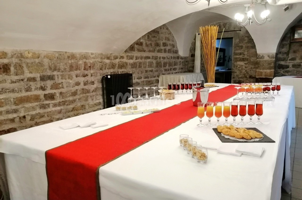 Table dressée avec une nappe blanche et un chemin de table rouge, garnie de verres de cocktails et d'amuse-bouches.