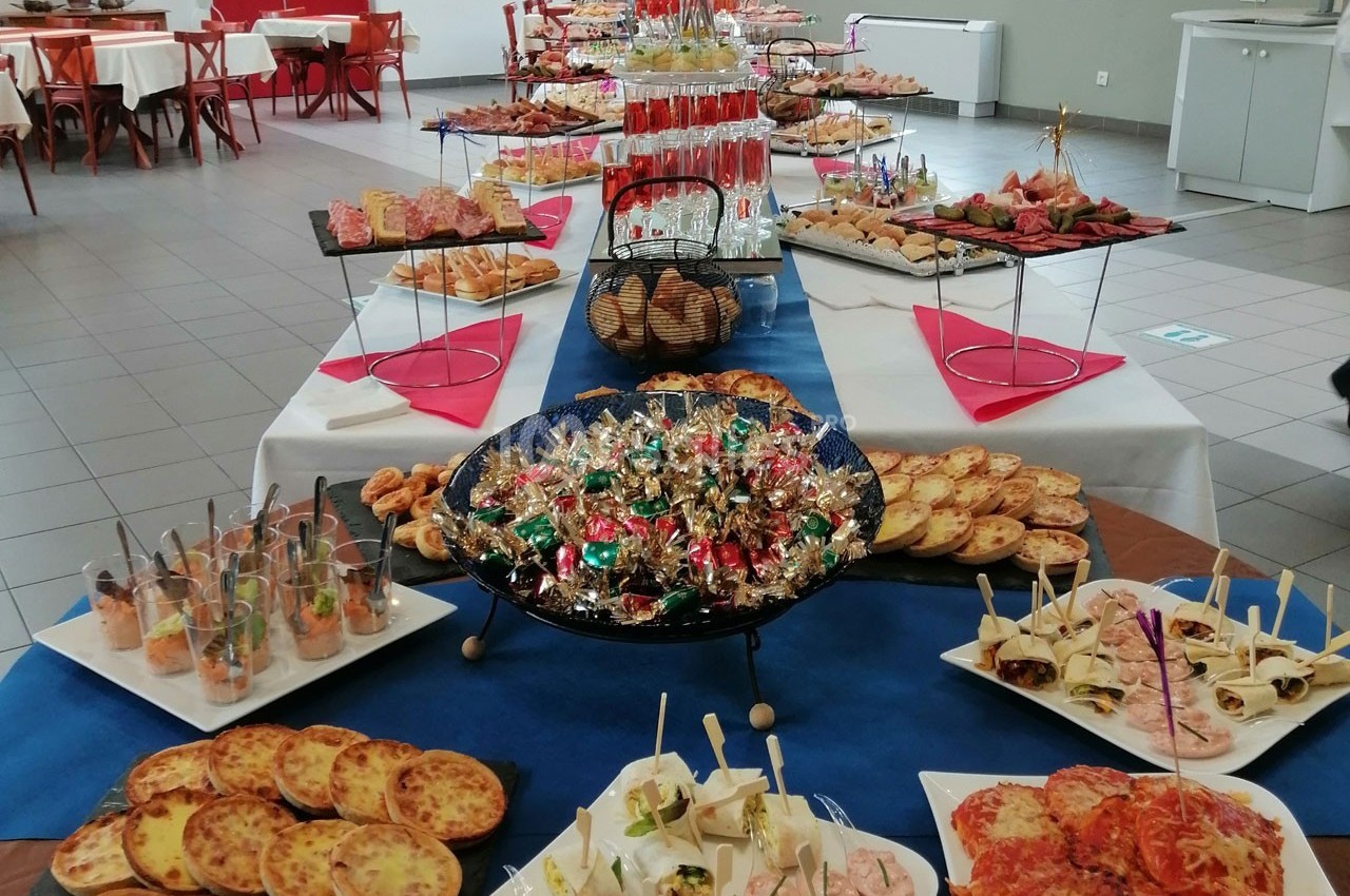 Buffet varié avec plats salés, verrines, amuse-bouches, pains et bonbons disposés sur une grande table.