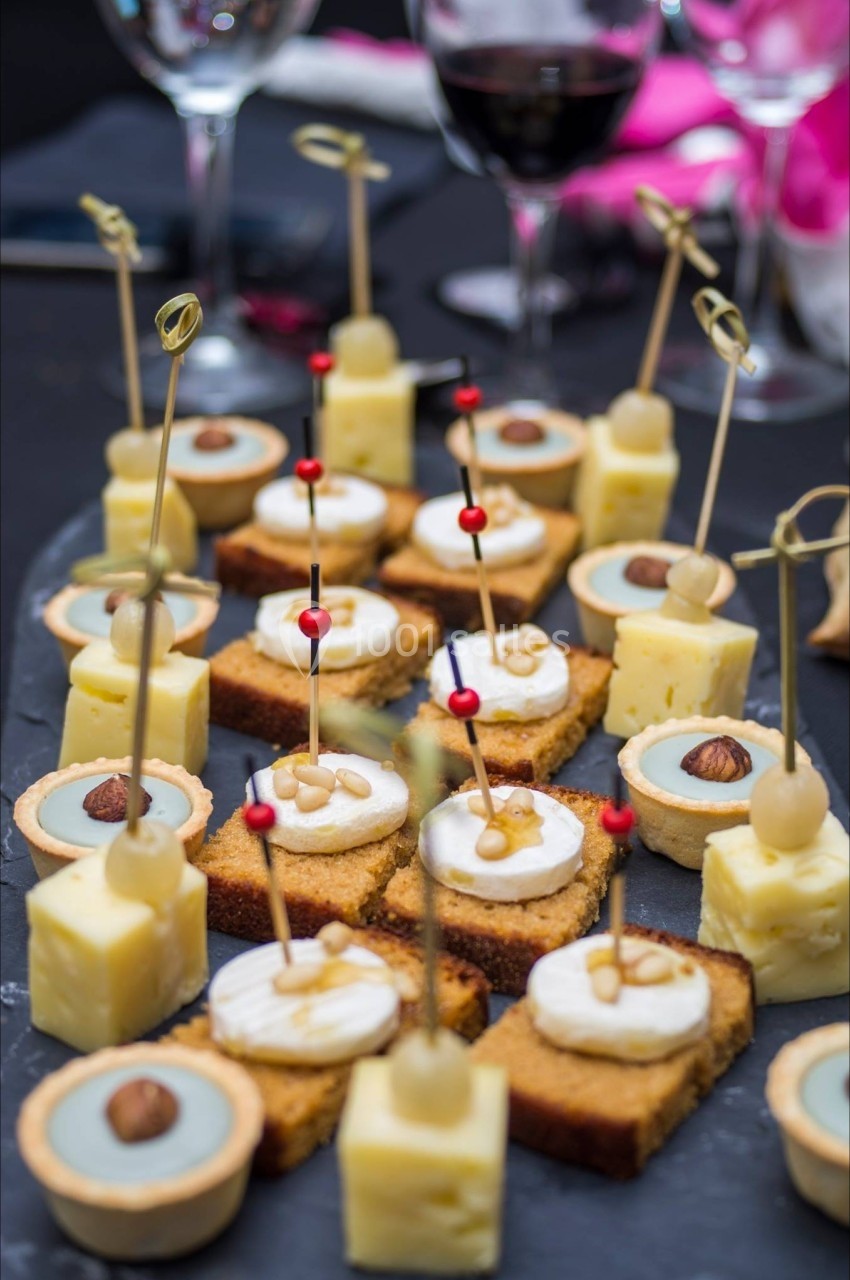Assortiment de bouchées apéritives sur un plateau, comprenant fromage, tartelettes et gâteaux décorés.